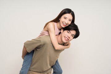 Fototapeta premium Piggyback ride Happy asian couple attractive in various action gesture standing on isolated white background. Cheerful Smiling young man and woman fun with piggyback ride