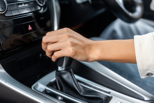 Young asian woman getting new car and his hand control the stick shift transmission in luxury car. Female hand changing gear driving car.