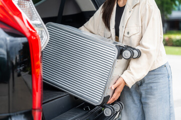 Young woman puts her suitcase in the back of the car and prepares to travel trip. Open the back of the car put luggage travel. Moving into new home at moving day