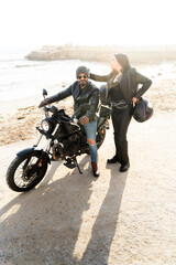 Bikers couple enjoying a sunny day at the beach with their motorcycle