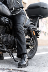 Naklejka premium Biker woman sitting on a motorcycle wearing black leather clothes and boots