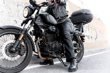 Biker sitting on a motorcycle wearing black leather clothes and boots
