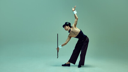 Graceful man bending dramatically while extending cane, embodying old-world charm in pinstriped...