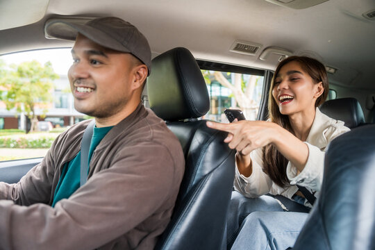 Young asian woman traveler talking with taxi driver explain the route how to travel in direction destination. Passenger showing the direction to taxi driver travel in city. Driver application service - Powered by Adobe