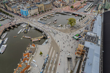 Fototapeta premium Beautiful aerial view of Amsterdam Centraal Train Station and its historic hub with canals, bikes, cafes. Netherlands