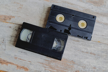 Two VHS cassettes lie on a wooden surface marked with scratches and the passage of time.  memories...