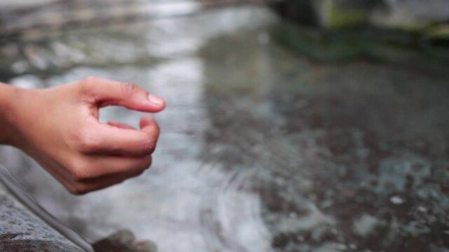 Hand drop whit thumb a coin to a fountain.