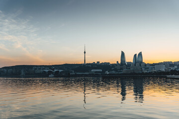 Naklejka premium top panoramic view of baku city with huge area with buildings flame towers symbol on sunset golden light and water reflections