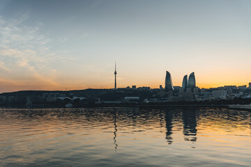 Naklejka premium top panoramic view of baku city with huge area with buildings flame towers symbol on sunset golden light and water reflections