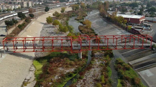 Aerial shot of Taylor Yard Bicycle and Pedestrian Bridge in Los Angeles. California. Modern red bridge and river.