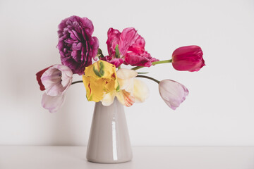 Beautiful bunch of multicolored terry tulip flowers in full bloom in vase against white background. Minimalist spring still life.