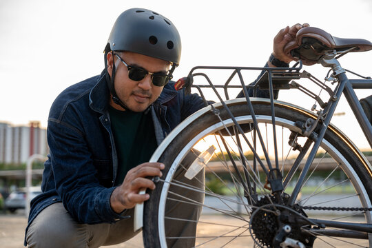 Asian traveler man broken down bicycle. Fix the bicycle wheel beside the street road. Stressed tourist man with bike