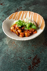 Delicious Asian chicken dish served in a decorative bowl, featuring tender pieces of chicken, colorful vegetables, and fragrant rice, garnished with fresh herbs.
