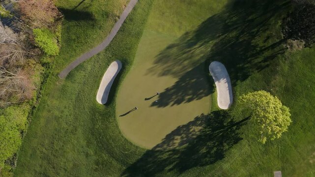 A Peaceful Aerial View Of A Golf Course With Players Competing And Groundskeepers Maintaining The Field. The Footage Highlights The Tranquility Of The Golf Course and the Hard Work Behind Its Care.