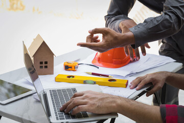 Engineers and architects pointing at laptop screens looking at blueprints. Two Construction Engineers or Architects discussing at work with laptop on construction site and pointing on laptop.