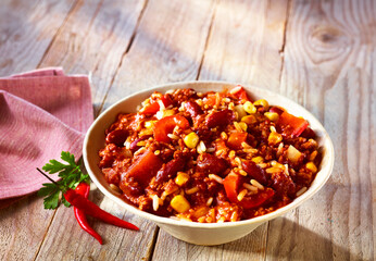 Chili sin carne mit Chilideko und rosa Serviette auf rustikalem Fond, mexikanisch, Bohnen, vegetarisch, 