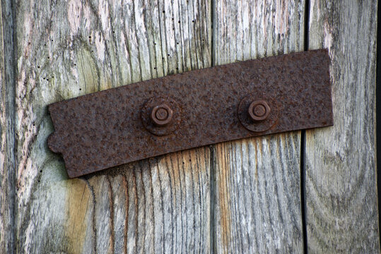 A rusty piece of iron is bolted to an old wooden door
