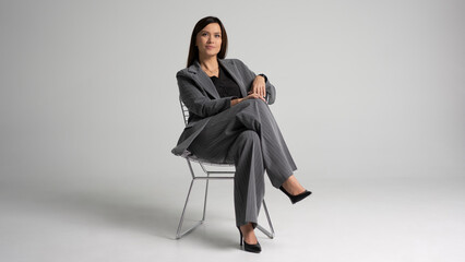 Portrait of a cheerful young businesswoman sitting in a chair against white background.