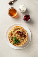 Large pancakes on a light stone background are served by a female cook, top view, home cooking, Maslenitsa, Easter