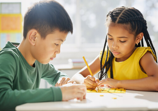 Two young kids are concentrating on solving math problems together at school