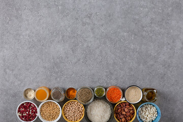 Set of vegan products on grey stone background with copy space, Cereals, beans, spices, chickpeas, olive oil, rice, chia, grains