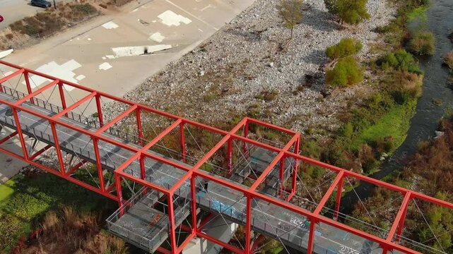 Aerial shot of Taylor Yard Bicycle and Pedestrian Bridge in Los Angeles. California. Modern red bridge and river.