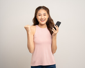 Naklejka premium Pretty young asian woman using cellphone standing on isolated white background. Happy Excited Beautiful young asian shopping online payment with mobile phone. Playing game on smartphone