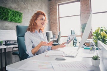 Photo of successful young business woman speak video call hold document modern loft interior office indoors