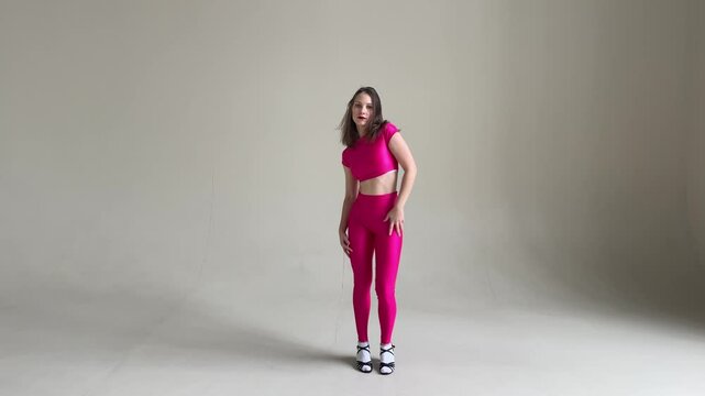 Elegant Woman Dancing Salsa in Pink Costume on Gray wall