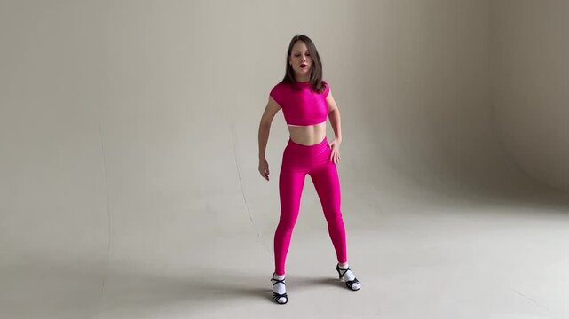 Elegant Woman Dancing Salsa in Pink Costume on Gray wall