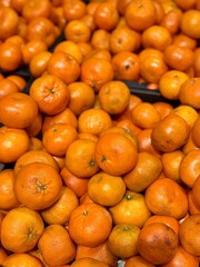 Box with ripe fresh organic tangerines on the shelf of a fruit supermarket are displayed for sale. Close-up