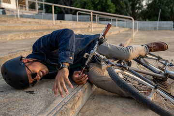 Asian tourist man falling off bicycle in city. Accident Injury leg pain. Broken leg Cyclist falls...