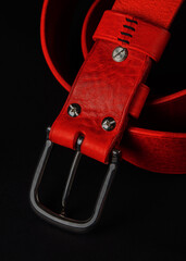 A red belt with silver studs on it. The belt is made of leather and has a black buckle