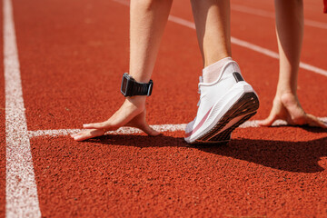 Female athlete at the starting line on a running track, preparing for a sprint, focused and determined for race competition and peak performance