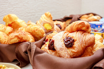 A selection of fresh pastries, including croissants and chocolate fillings, beautifully arranged in baskets lined with brown fabric. The golden brown color of the baked goods is inviting.