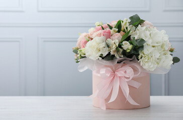 Beautiful bouquet in box on white wooden table. Space for text