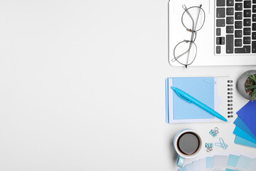 Designer's workplace with stationery, color palettes, cup of coffee and laptop on grey table, flat...