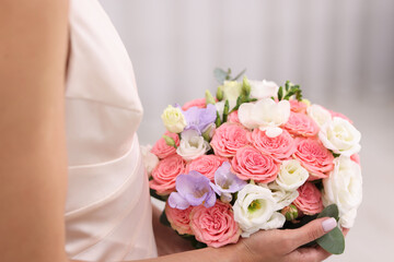 Bride with beautiful wedding bouquet on light background, closeup