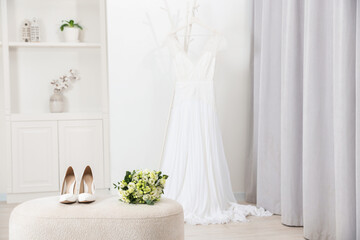 Beautiful wedding bouquet and bridal shoes on pouf indoors