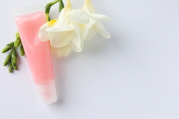 Lip balm and freesia flowers on white background, flat lay. Space for text