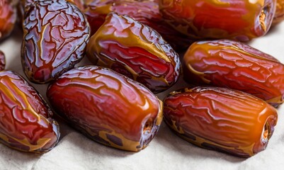 Raw organic medjool dates ready to eat on the table. Organic raw big date fruit texture background. Many beautiful bright dried dates on light background. Detailed close-up.