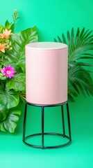Pink cylindrical container on a black metal stand against a green background, surrounded by lush tropical foliage. 