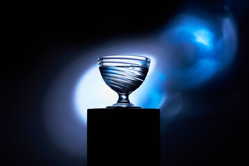 Transparent Glass Cup on Black and Blue Glowing Background
