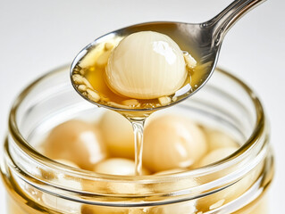 Spoon lifting a pickled pearl onion from a glass jar