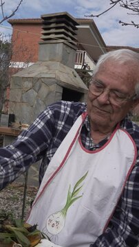Eighty-year-old man eating cal&ccedil;ot in the open air. Dressed with a bib painted with an onion and a checked shirt.