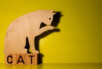 Silhouette of a cat made of plywood on a yellow background