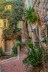 Charming Old Town Street In Menton: Narrow Cobblestone Alley With Colorful Mediterranean Buildings, Green Wooden Shutters, Hanging Laundry, Potted Plants, And Aged Facades In The French Riviera