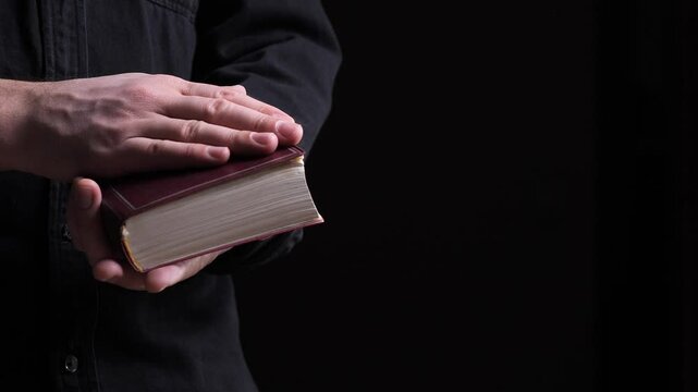 Priest holding holy bible, praying and reading in church