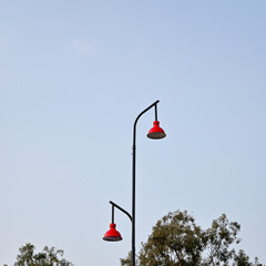 Black street lamp post with two curved arms, each supporting a red, industrial-style lamp shade. 