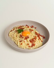 Creamy Pasta Dish with Egg Yolk and Crispy Bacon on White Background